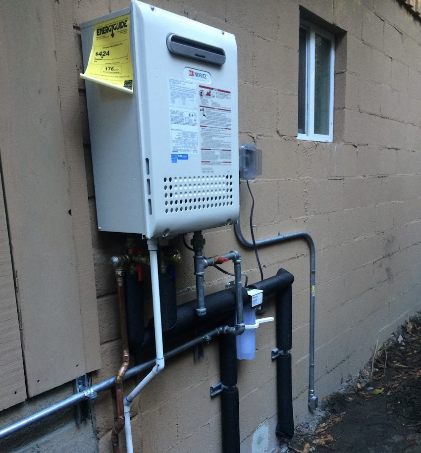 Noritz tankless water heater installation on exterior wall with copper and gas piping